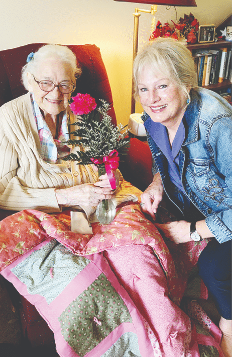 daughter giving elderly mom flowers