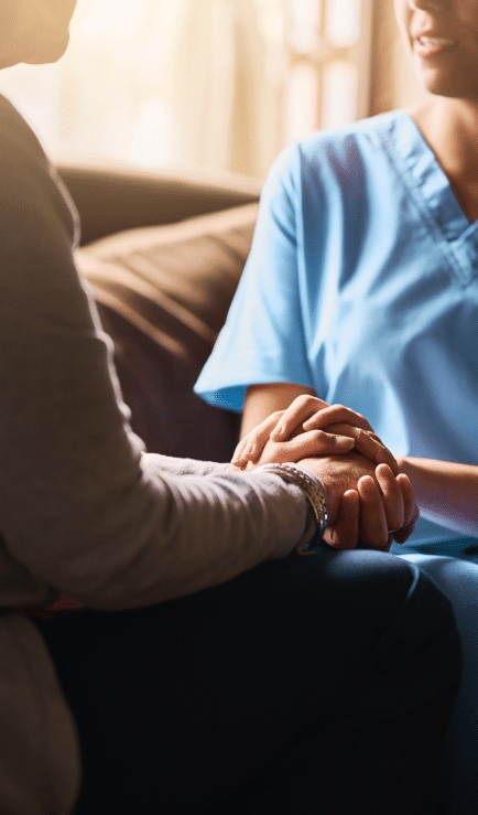 nurse and patient embracing hands talking on a couch